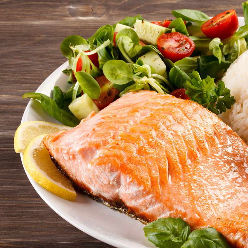 Salmon Fillet On A Plate wwith Salad Lemon and Basil Garnish